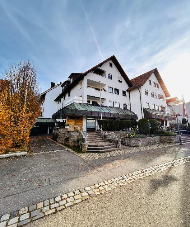 Mehrfamilienhaus mit gepflasterter Einfahrt und Vorgarten im Herbst