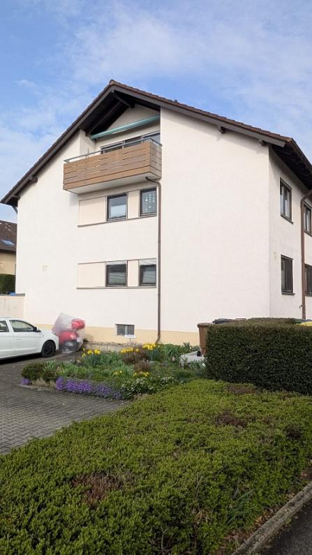 Helles Wohngebäude mit gepflegtem Garten und Hecken