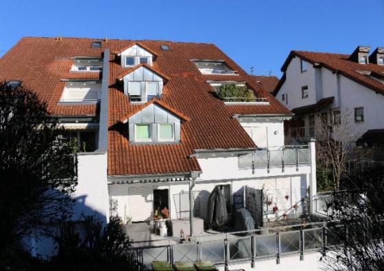 Mehrstöckiges Wohngebäude mit roten Ziegeldächern und Balkonen